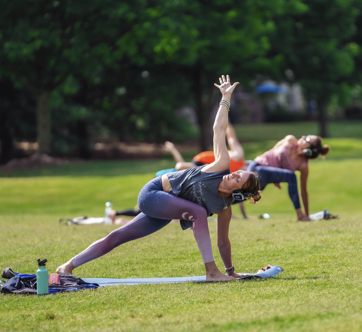 Adults doing yoga in a park3