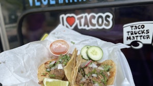 Two tacos in to-go container near International Truck of Tacos1