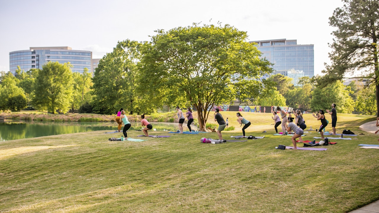Adults doing yoga in park at Ballantyne campus3