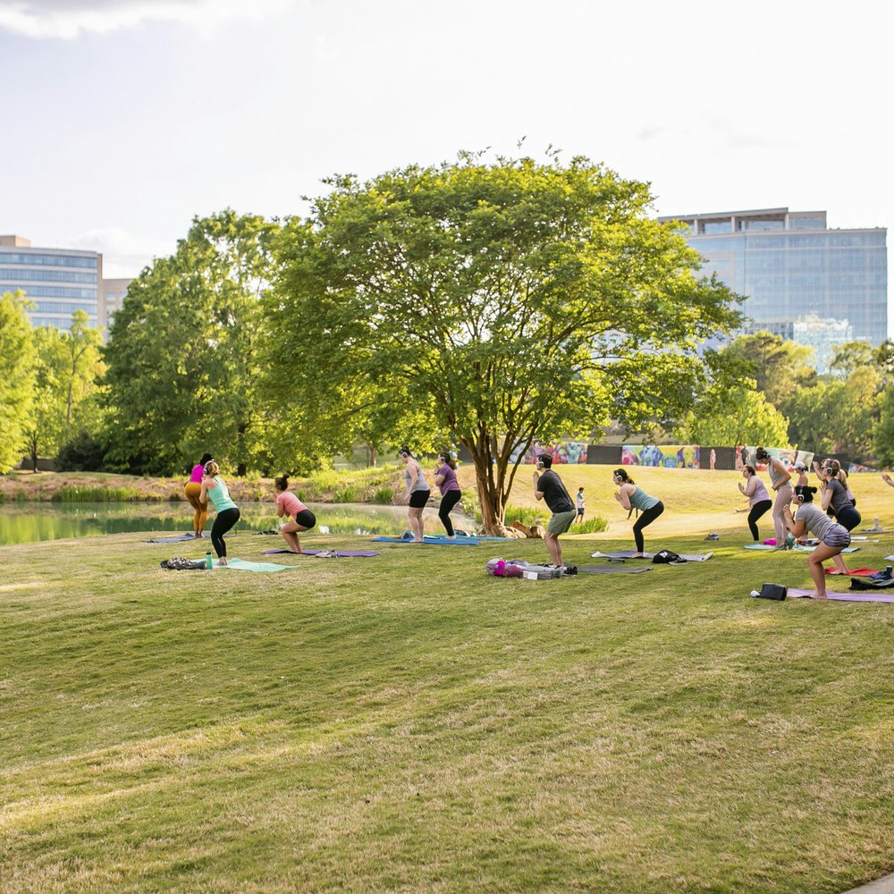 Adults doing yoga in park at Ballantyne campus