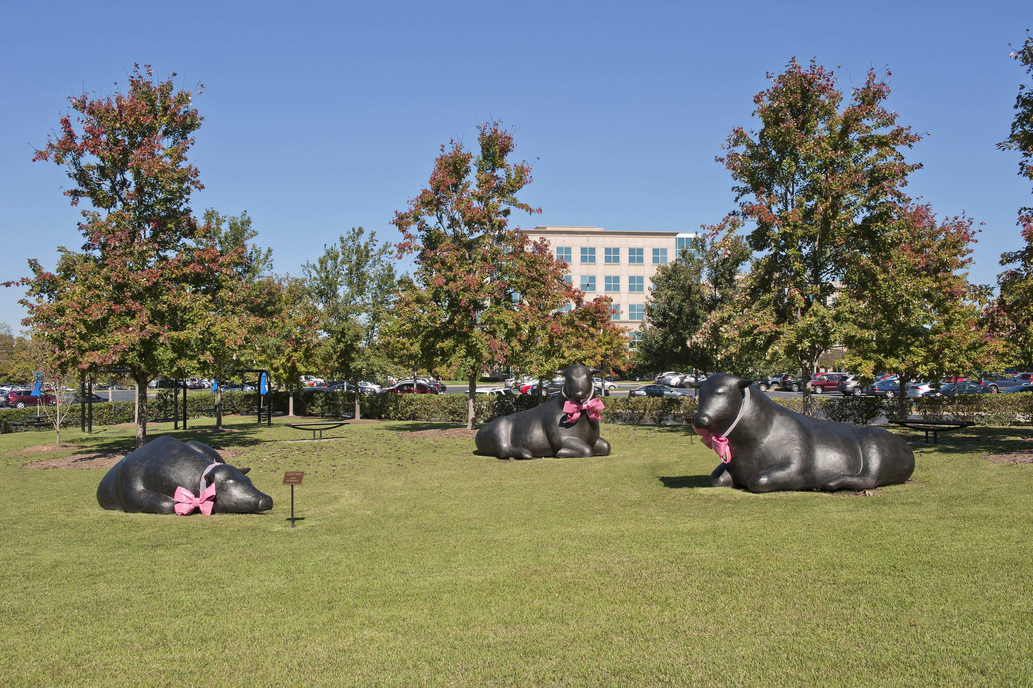 Statues of bulls in park with pink bows on neck1