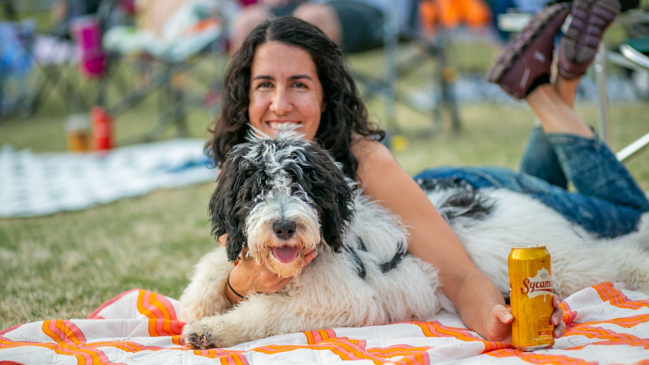 Young woman and dog lay on blanket in park5