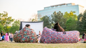 Young people sitting in park to watch a movie on outdoor screen4