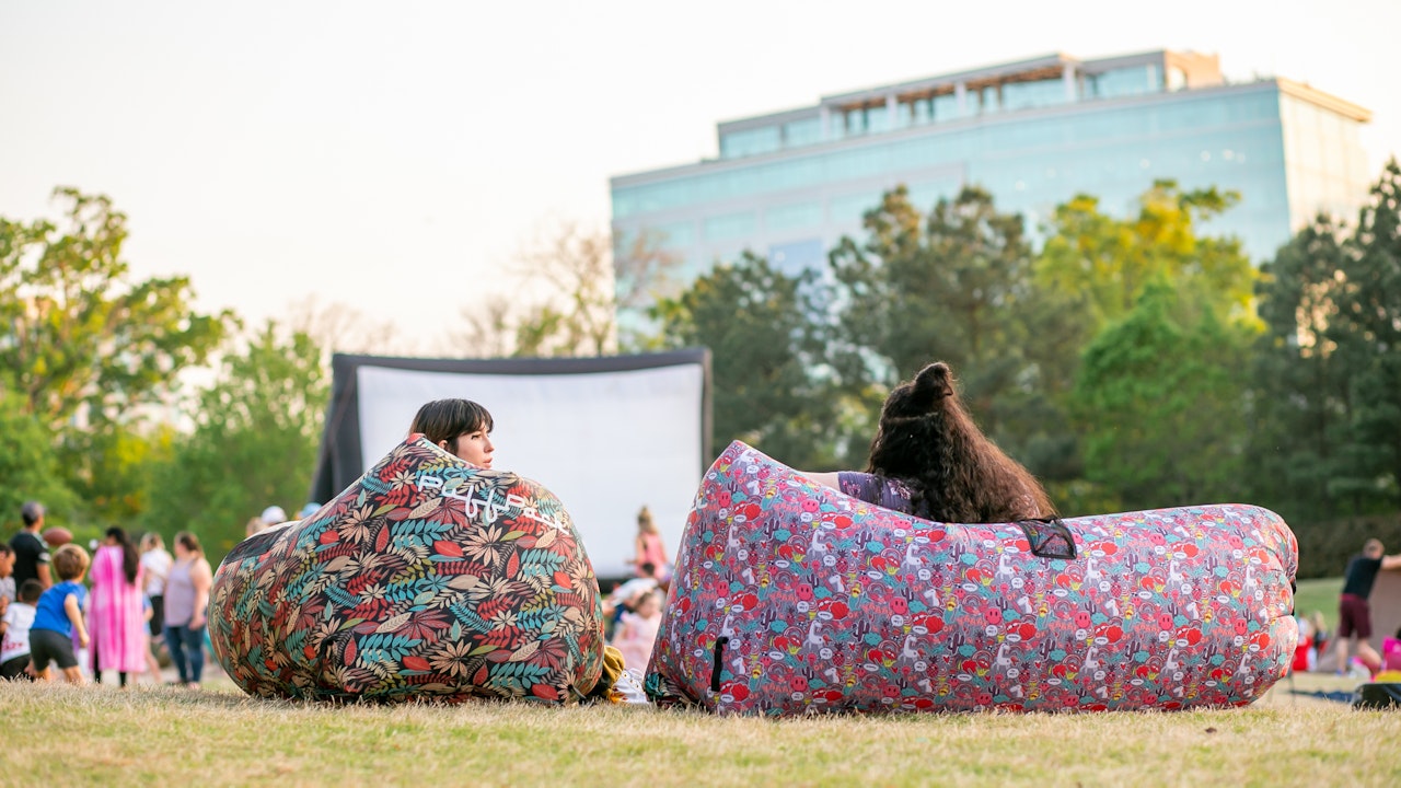 Young people sitting in park to watch a movie on outdoor screen1