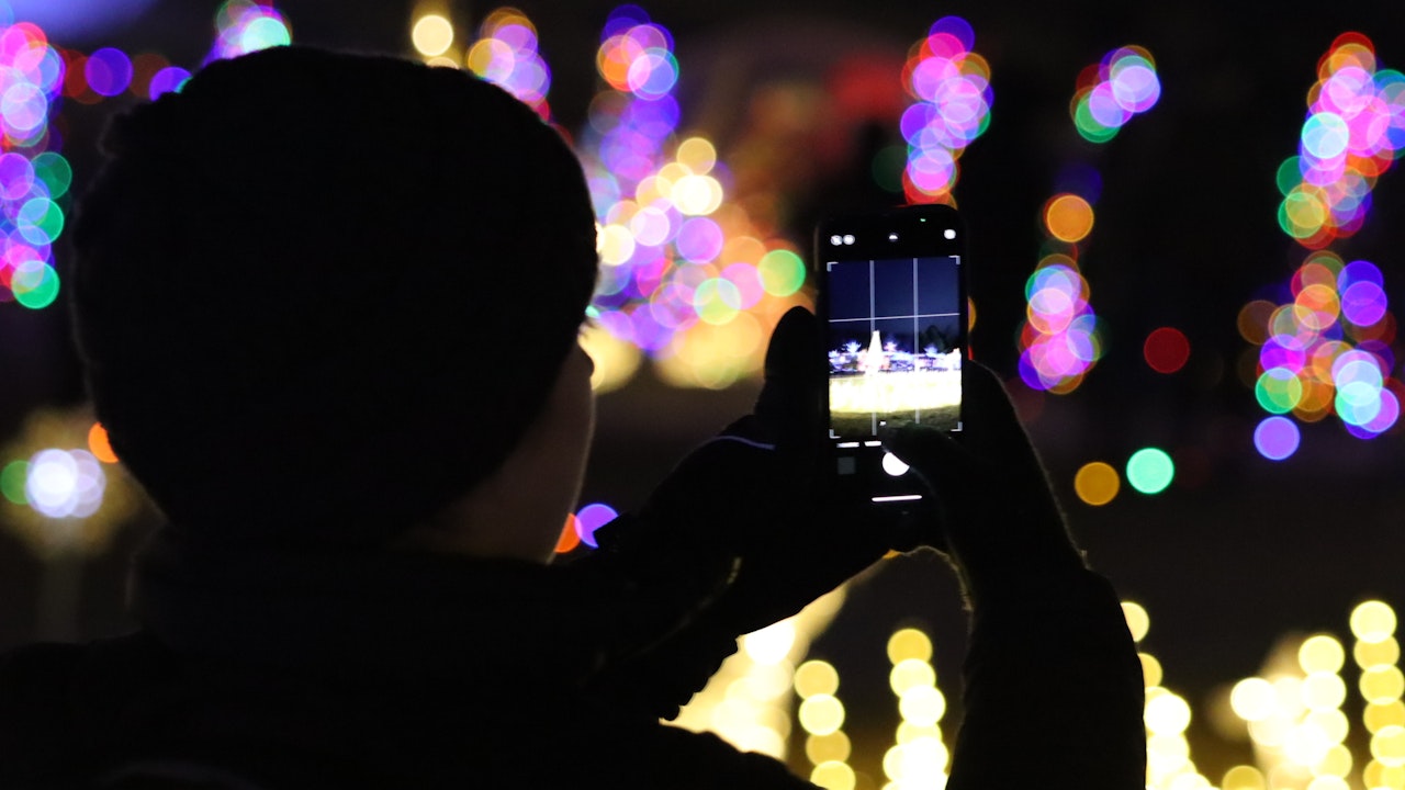 Woman taking a photo of an exhibit at an outdoor holiday light show2