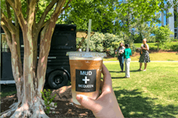 Hand holding iced coffee in outdoor park2