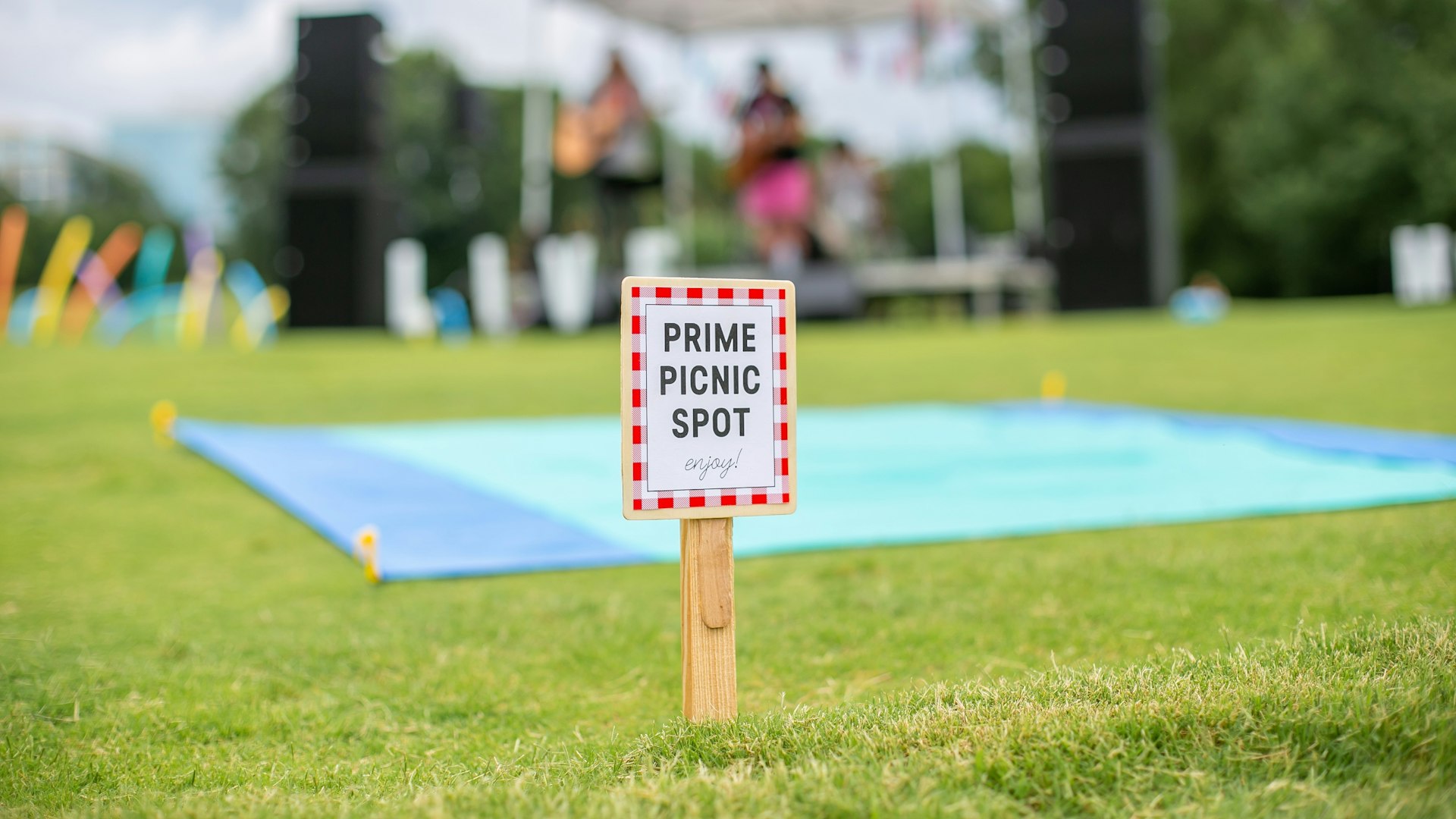 A picnic blanket on the grass in front of a live music stage.